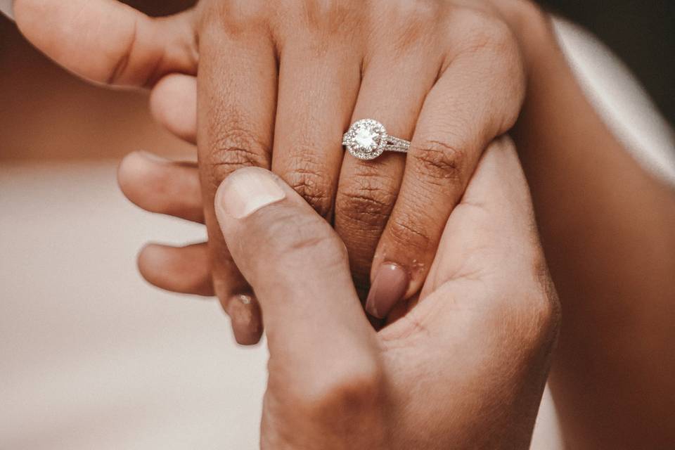 Bride showcasing incredible engagement ring holding partner's hand - 