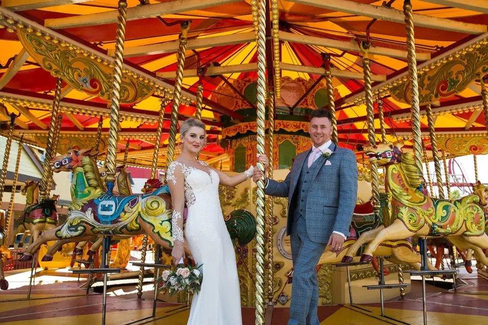 Bride and groom smiling at camera from fairground hobby horse ride