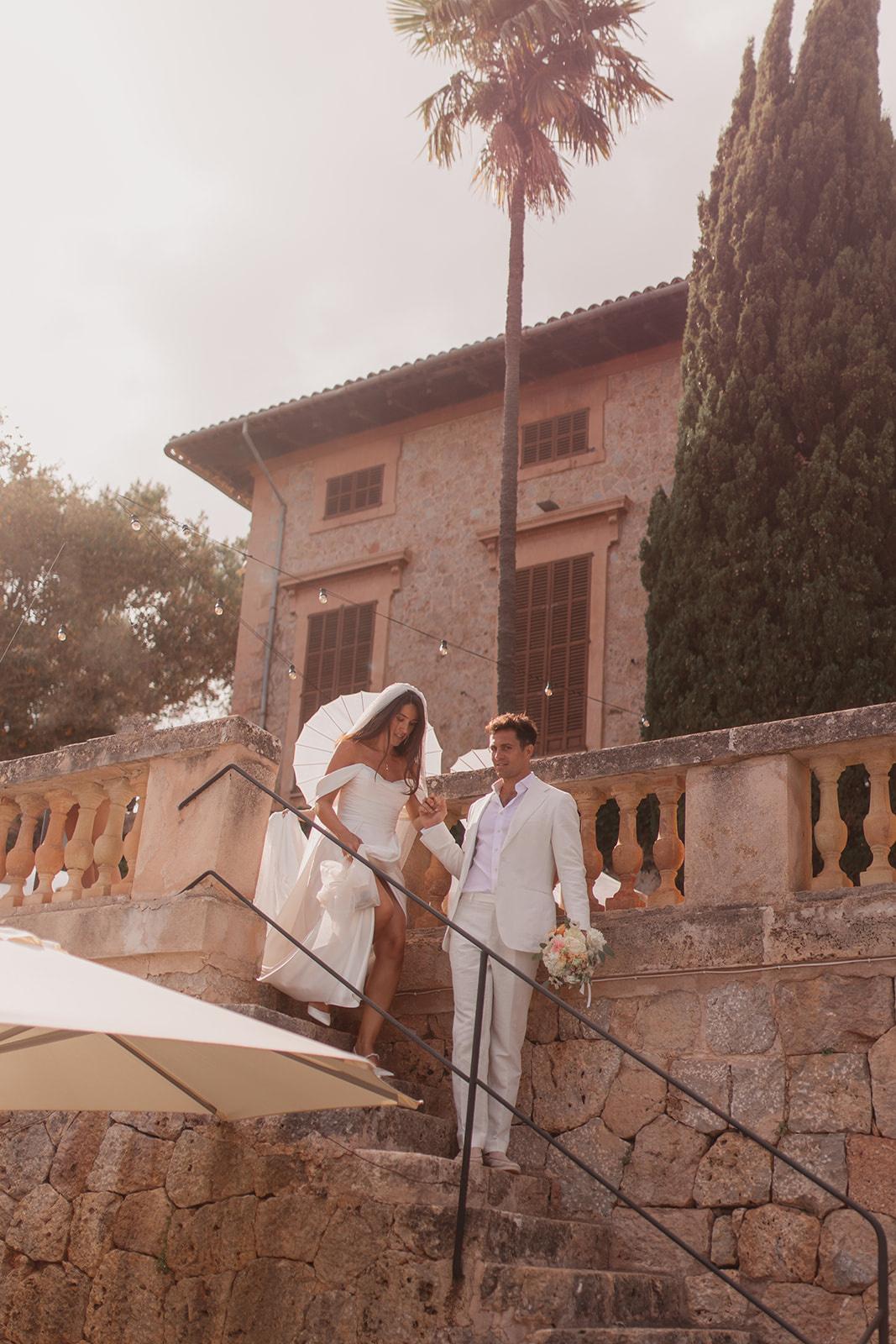 Josie and Cameron walking down the steps at their Mallorcan wedding venue