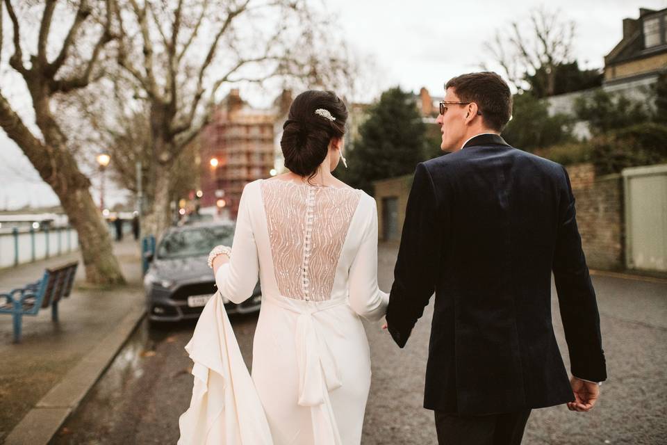 Bride and groom walking down a road in Putney alongside the River Thames