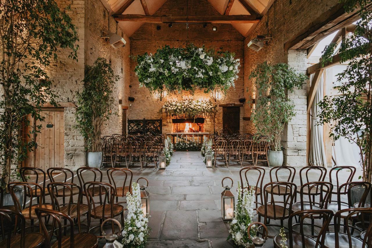 The interior of the stone barn decorated for a wedding with a roaring fire at the end of the aisle