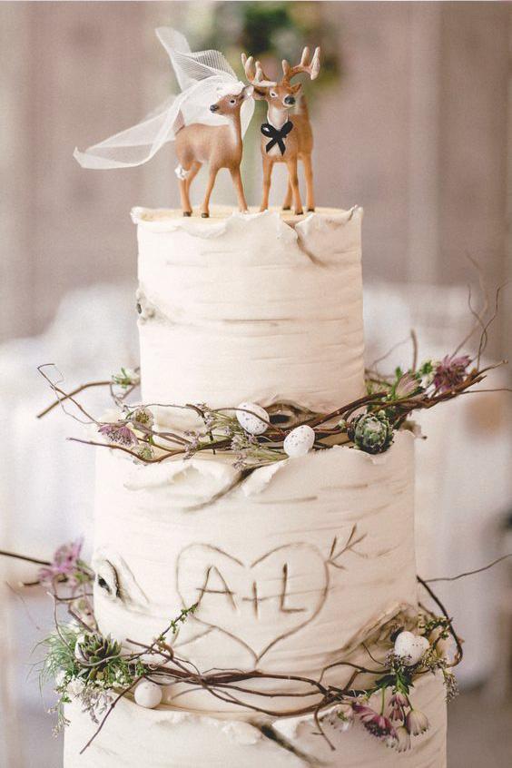 White rustic wedding cake with deer topper and branches