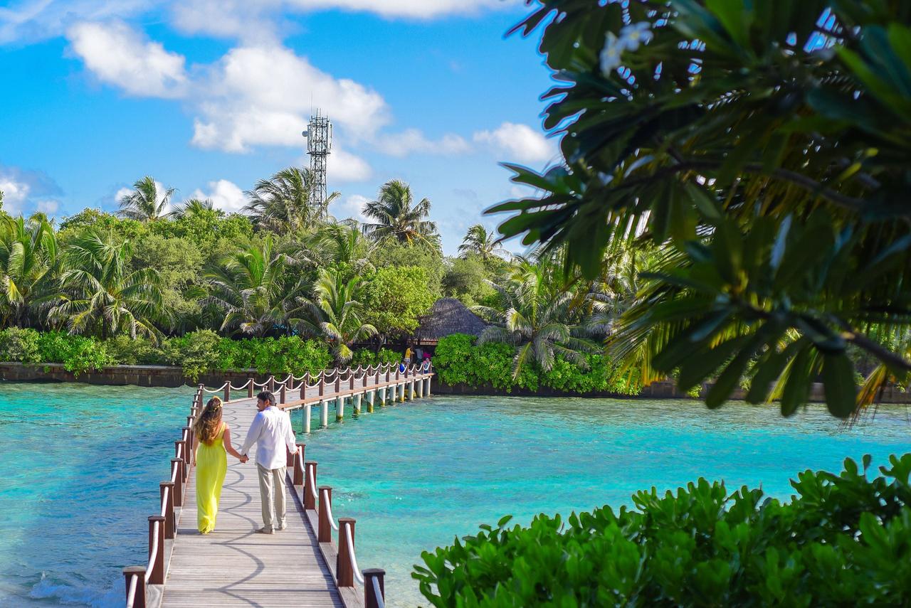 couple holding hands walking on bridge on their honeymoon in the maldives