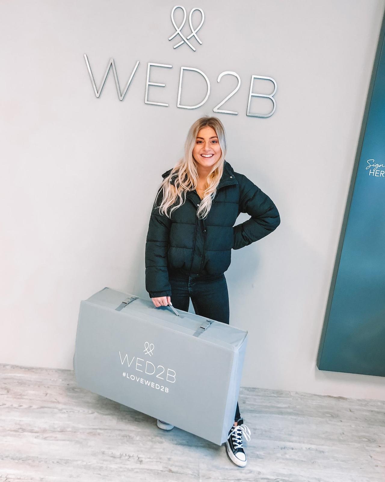 The writer holding a wedding dress bag