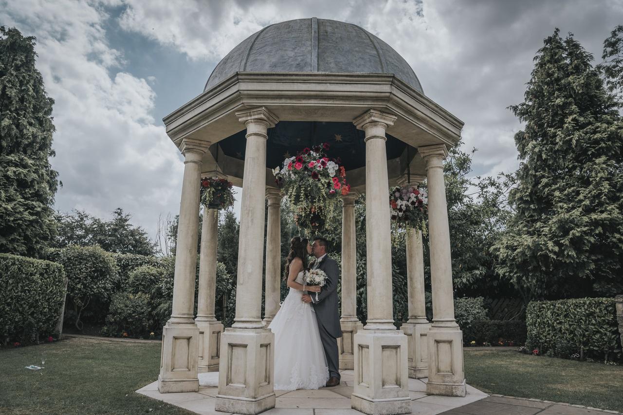 Wedding couple kissing in an outdoor stone pagoda