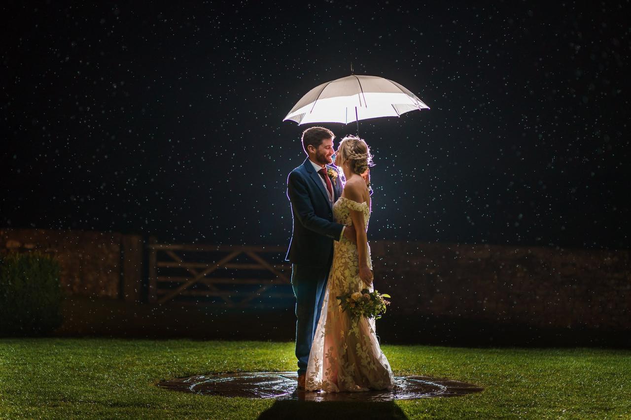 bride and groom standing under a white umbrella embracing beneath a night sky