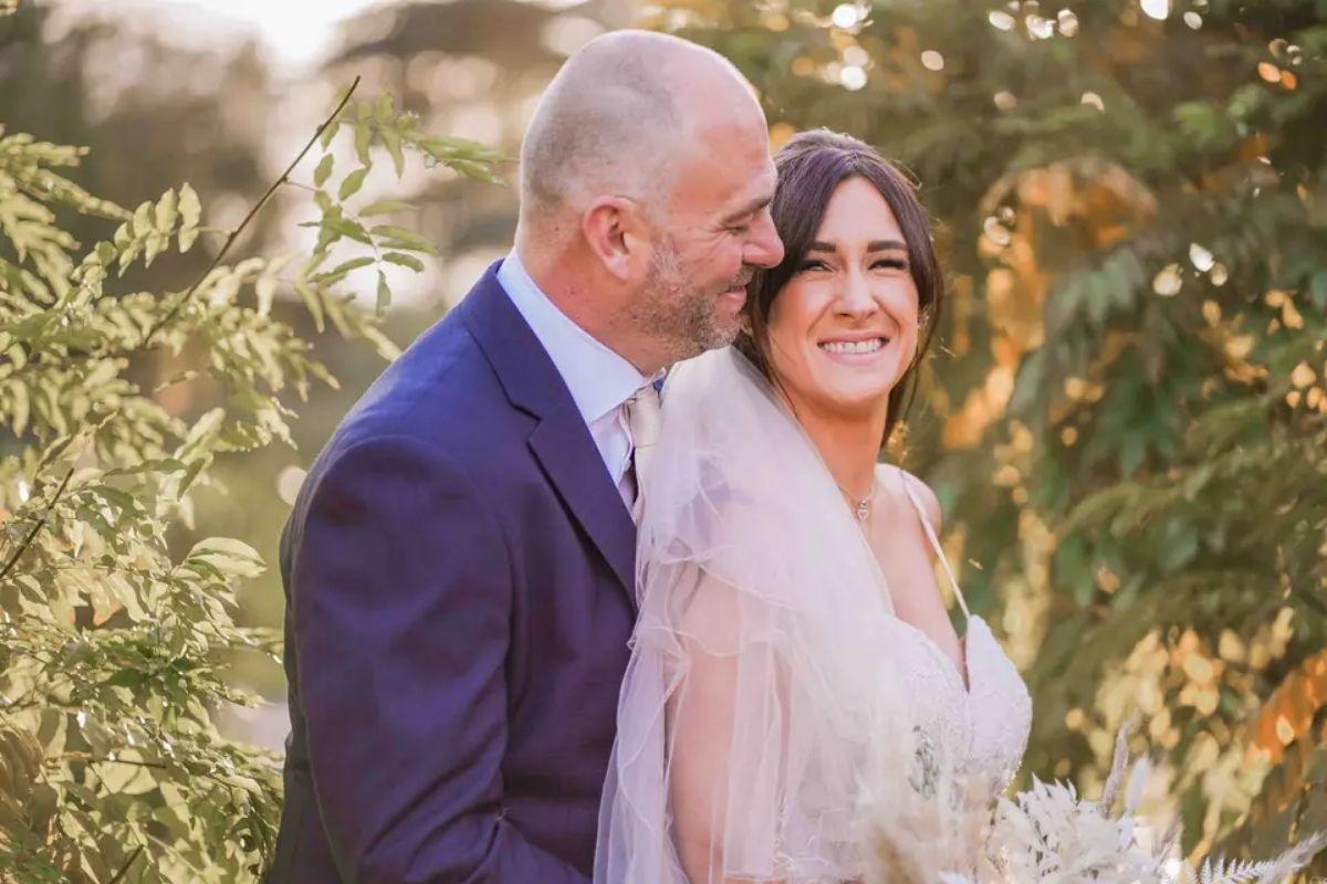 a bride smiles as she faces the side and has her groom behind her smiling