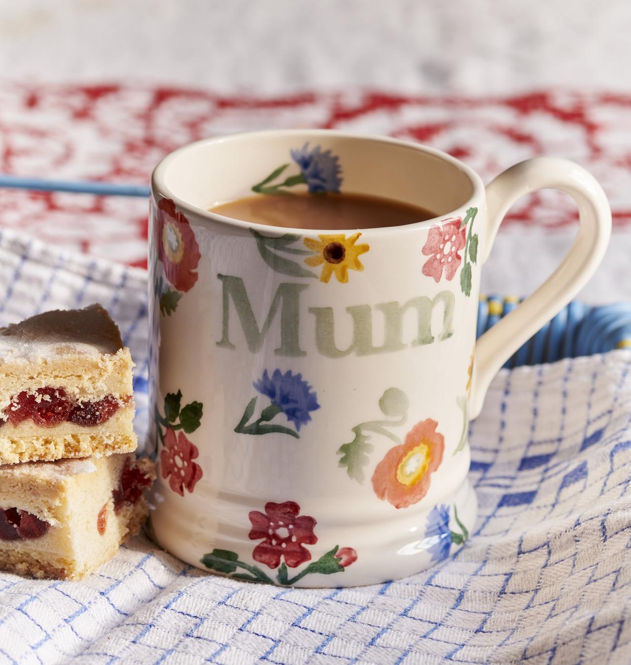 A hand-painted floral mug with the word 'mum' next to a stack of cake bites.