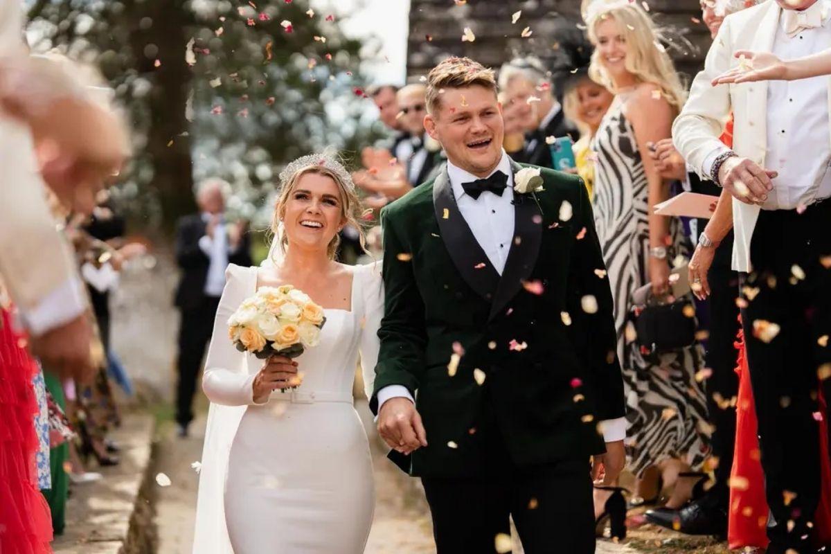 a bride and groom smile and look happy as guests throw confetti on them after their wedding ceremony
