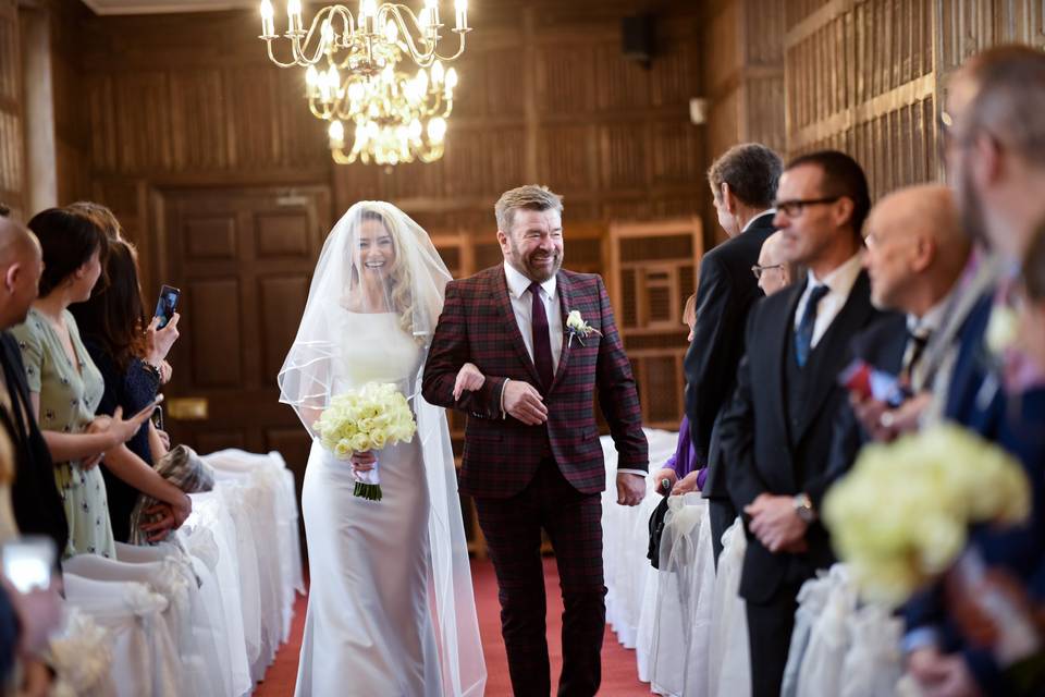 A bride walking down the aisle arm in arm with her father.