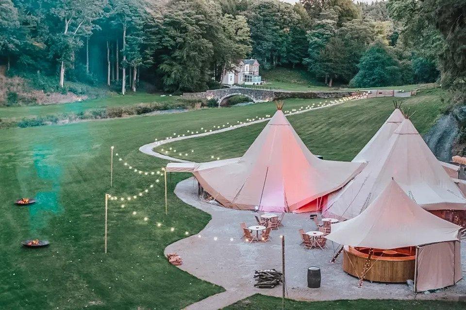 Aerial view of tipis with airy lights, bridge and house