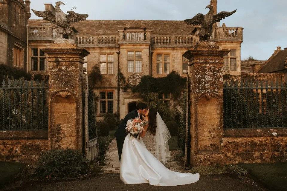 A bride and groom kiss in front of the exterior of Mapperton