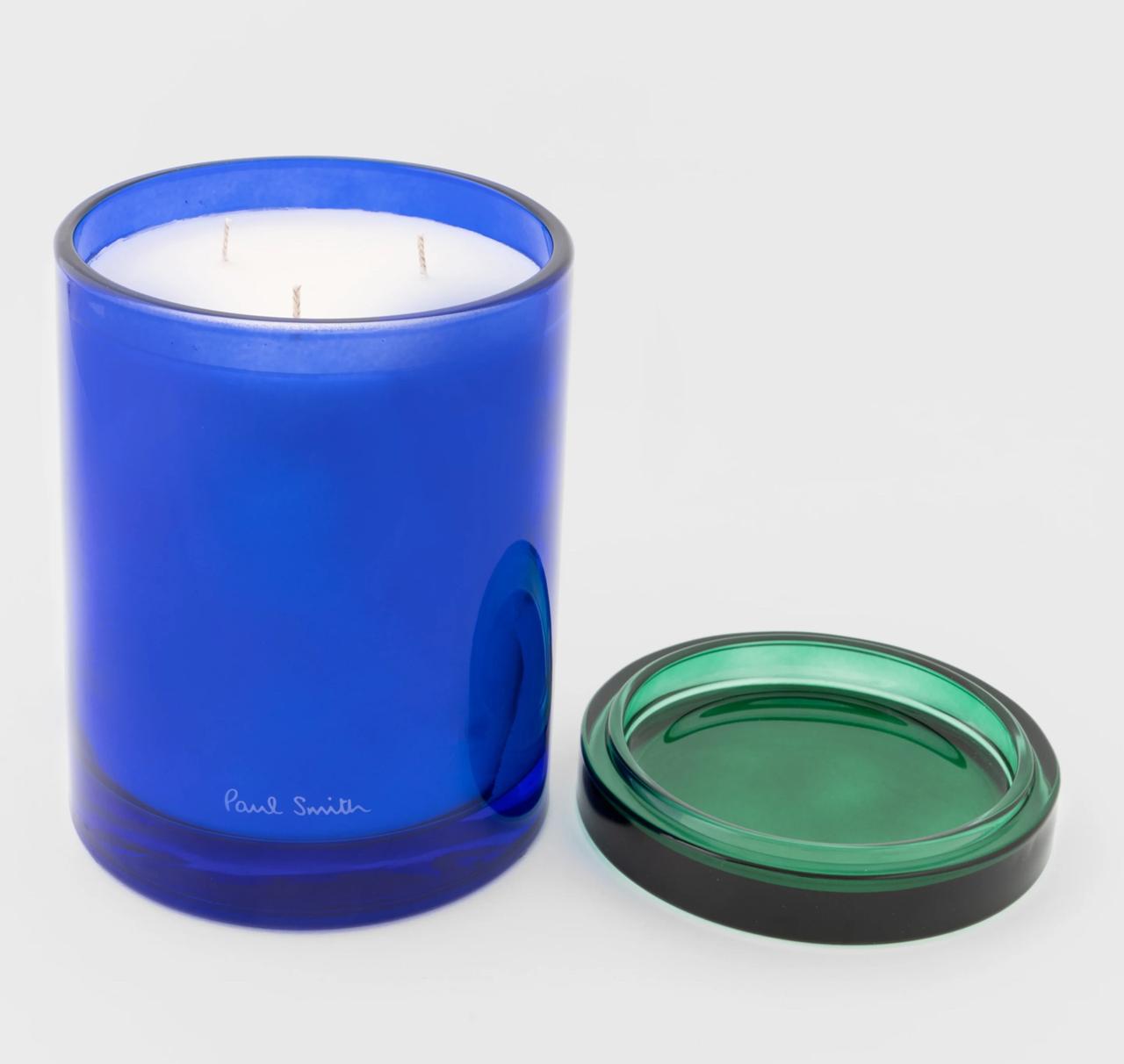 A three wick candle in a bright blue glass holder with a contrasting green lid (removed)