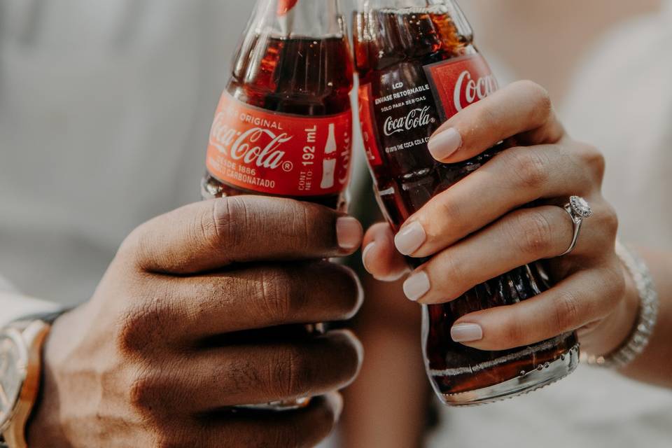 Couple clinking coke bottles together with an engagement ring visible in an Instagram engagement announcement