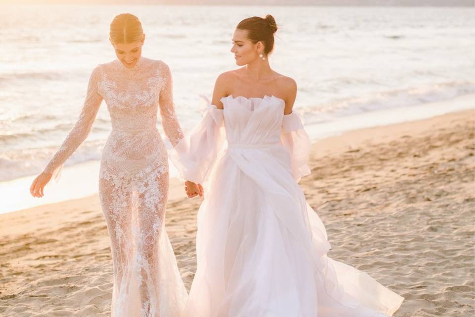 Bride and bride holding hands walking along the beach