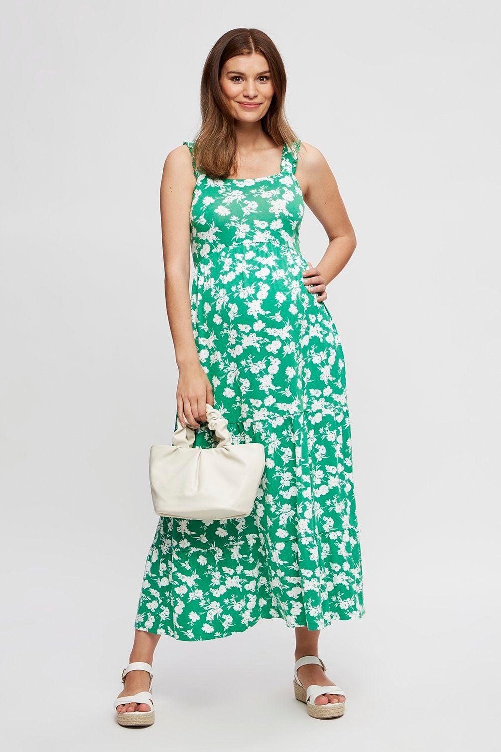 Pregnant model wearing a green floral wedding guest dress