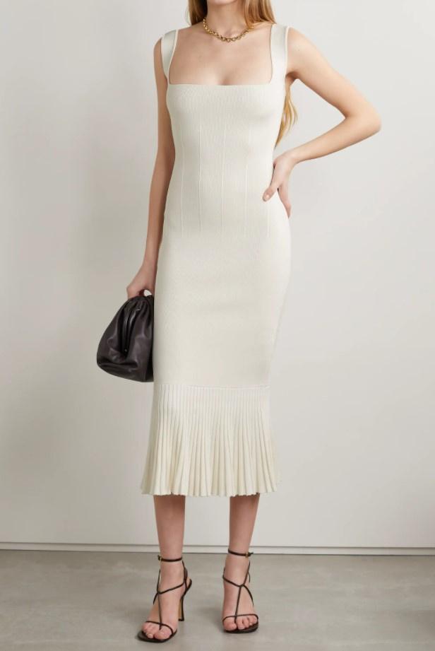 Model wearing a cream midi dress in a stretch-knit fabric with a square neckline, straps, and pleated details on the hem of the dress