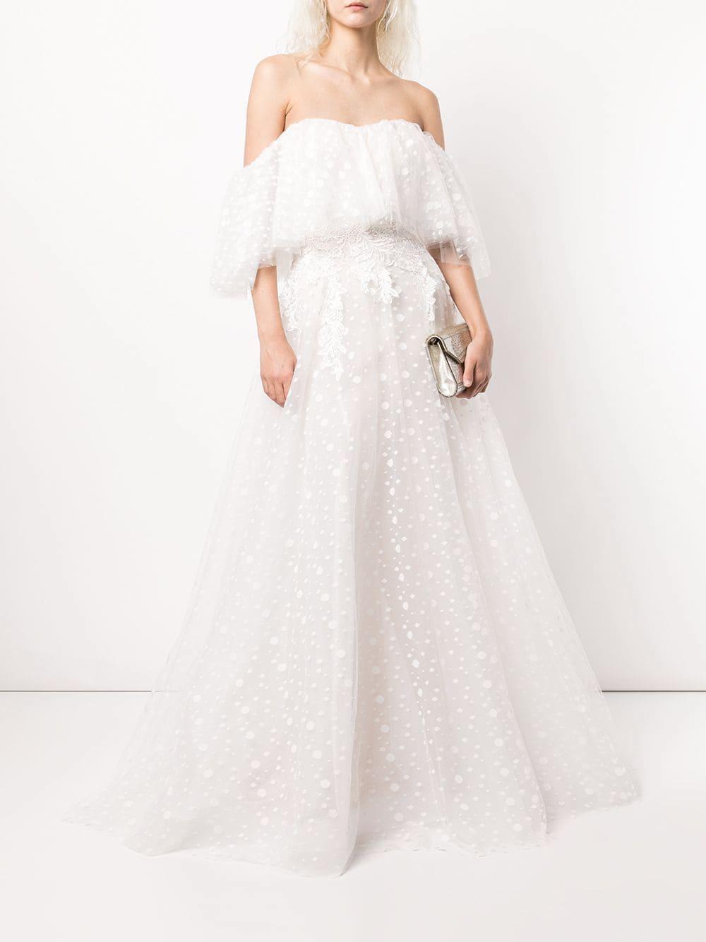 White woman with short platinum blonde hair wearing an off-the-shoulder dotted and floral lace wedding dress
