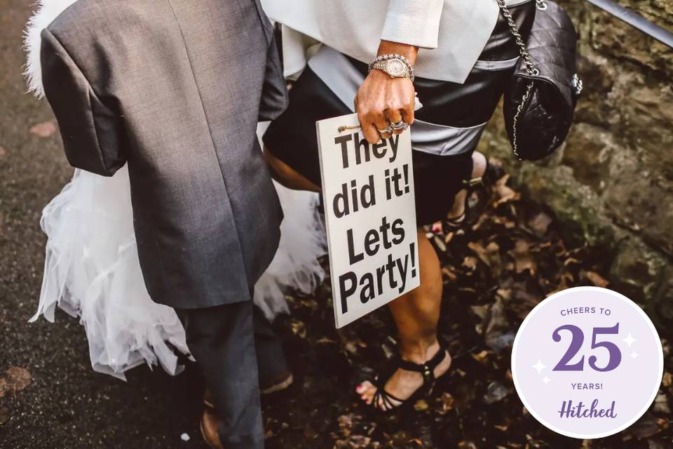 married couple holding a sign saying 'They did it! Let's Party!'