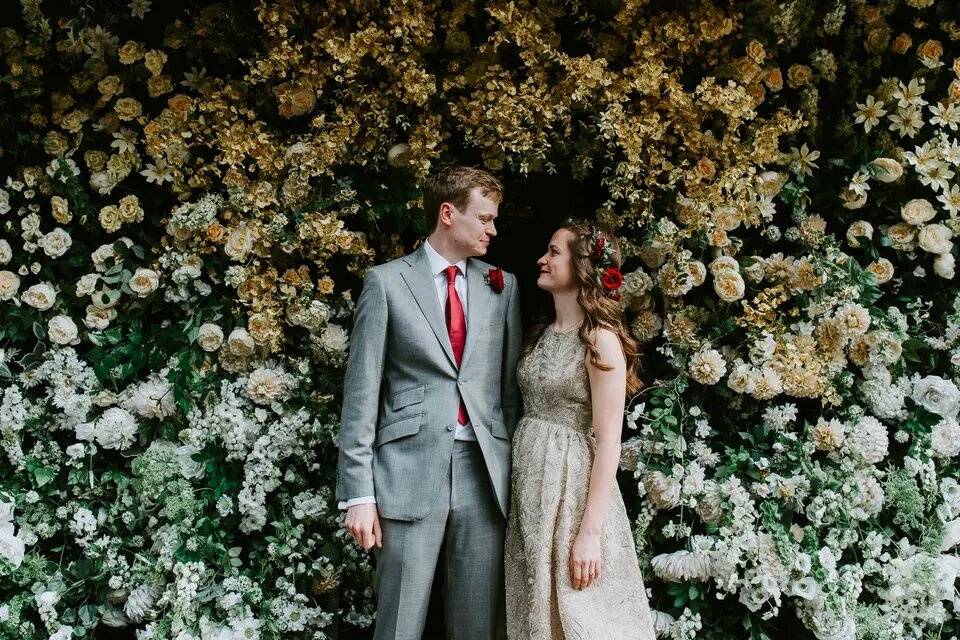 Bride and groom in front of a flower wall