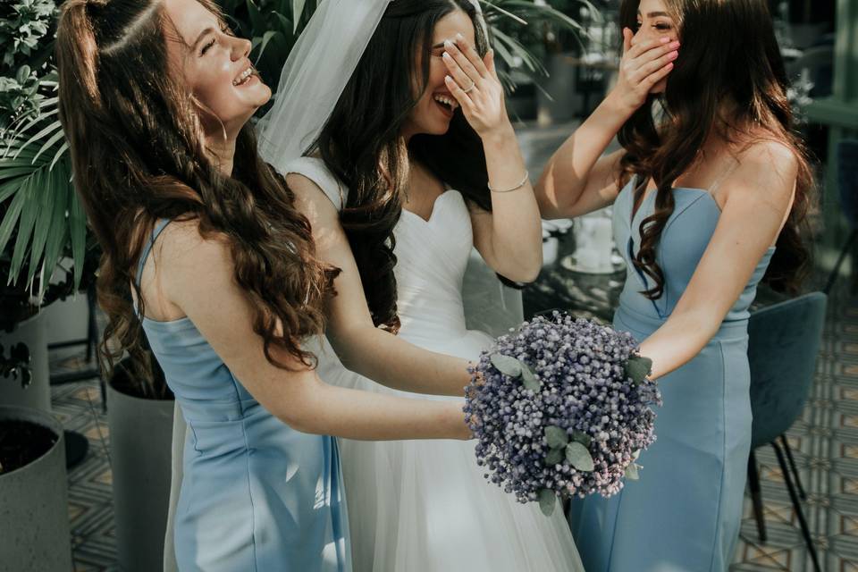 A bride and two bridesmaids laughing at a wedding