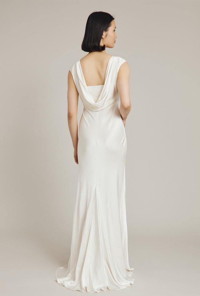 Model with her back to camera wearing a cowl back satin wedding dress
