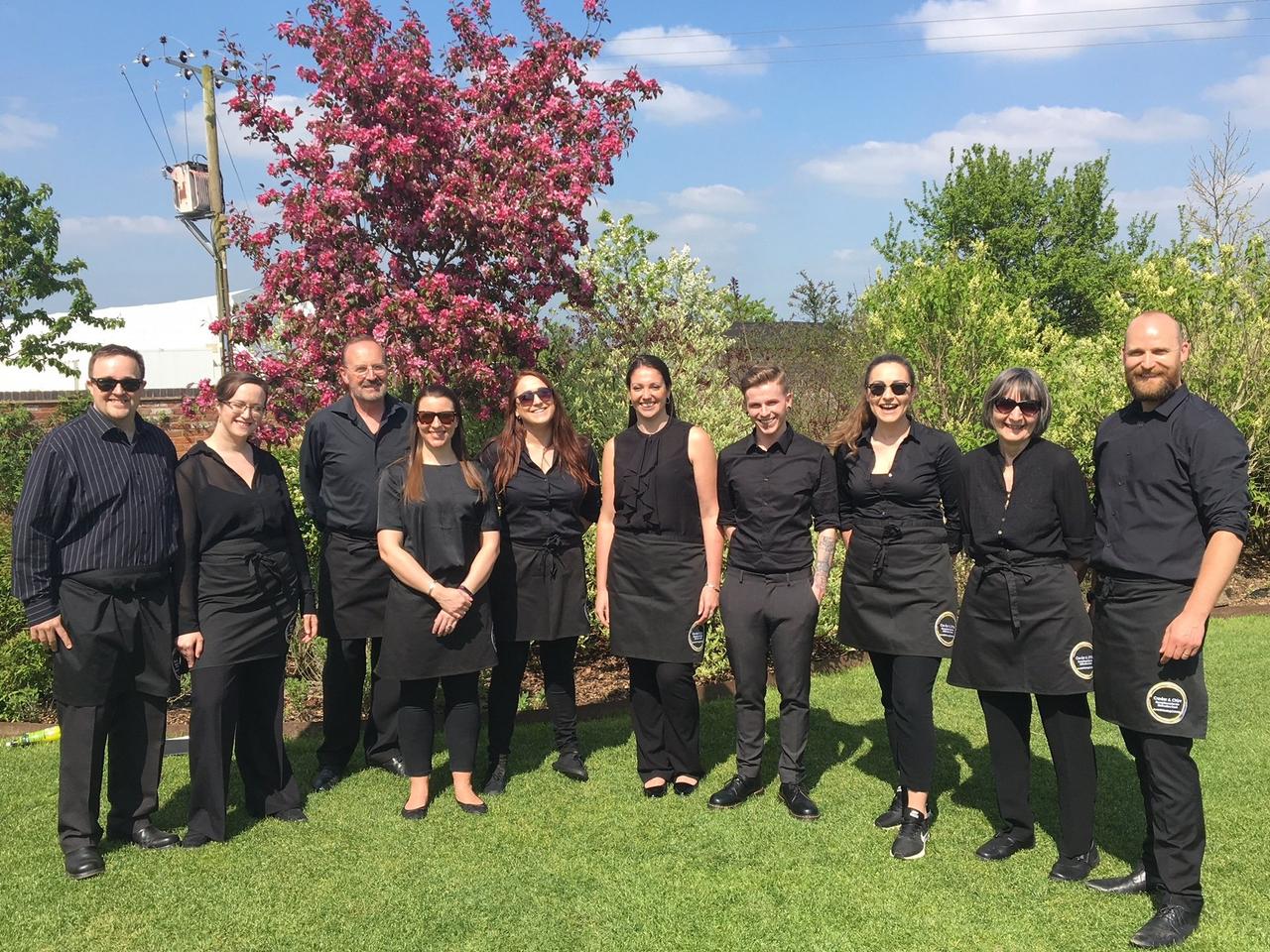 The Caviar and Chips wedding catering team posing outside in their black catering uniforms