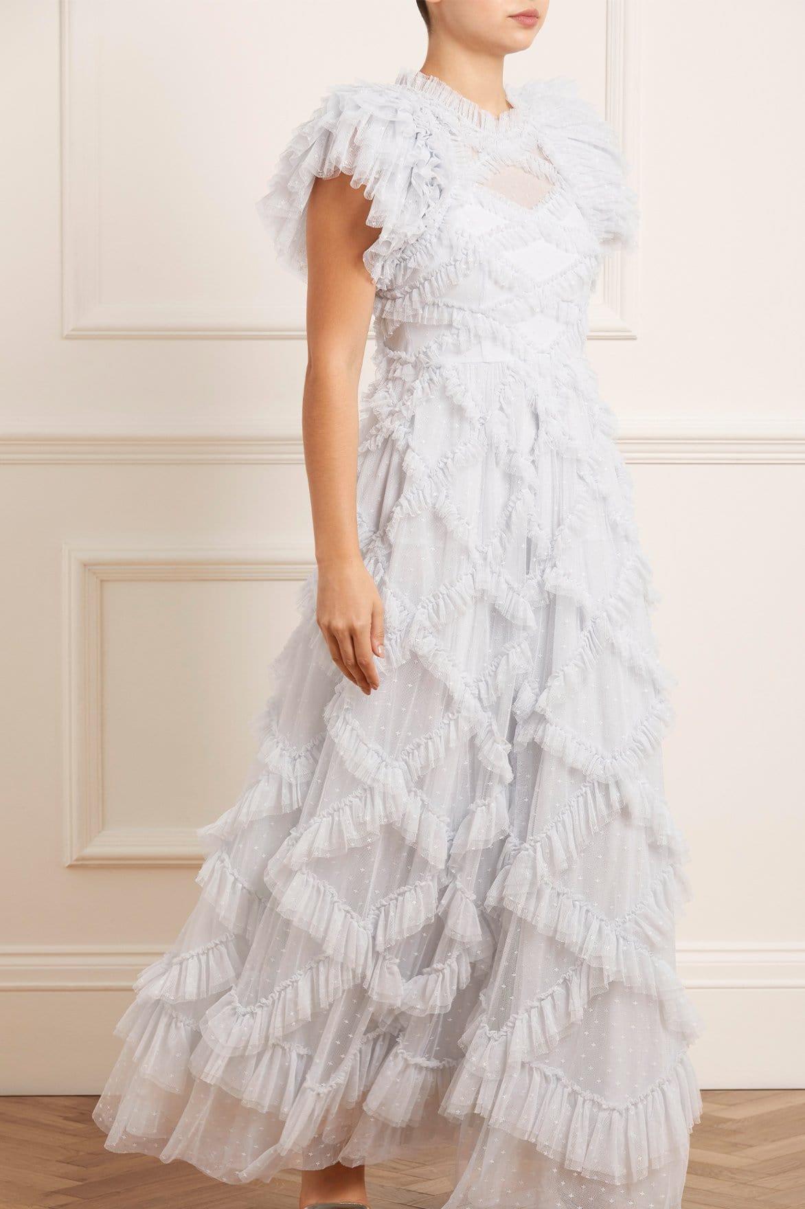 White woman with cropped dark hair wearing a diamond stitched high necked light blue tulle wedding dress with multiple tiers