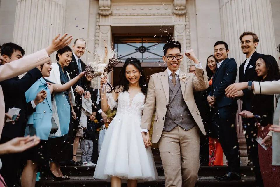 Bride and groom exit their ceremony surrounded by friends and family cheering