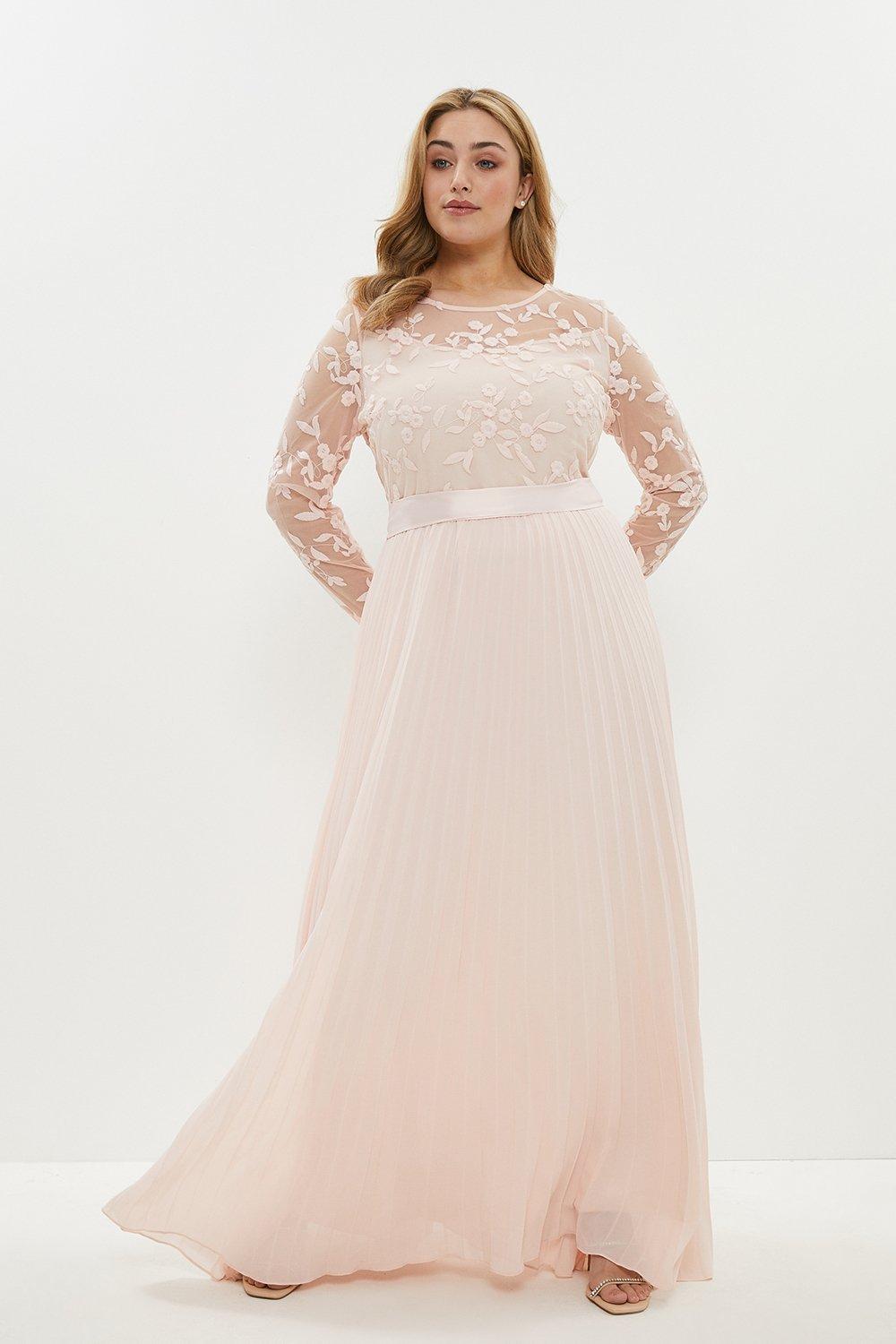 Model wearing a pink floral bridesmaid dress with pleats and long sleeves