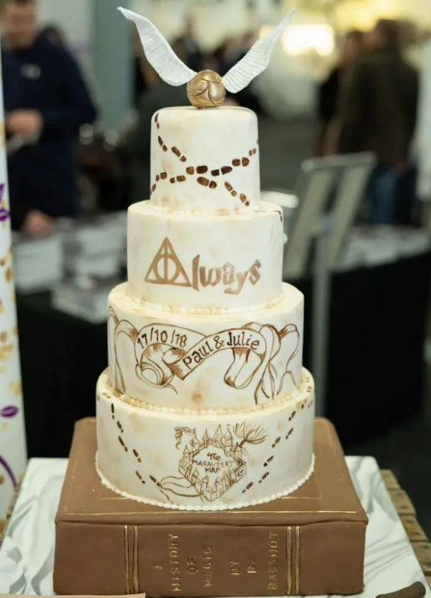 gold and white wedding cake with Harry Potter quotes and golden snitch cake topper