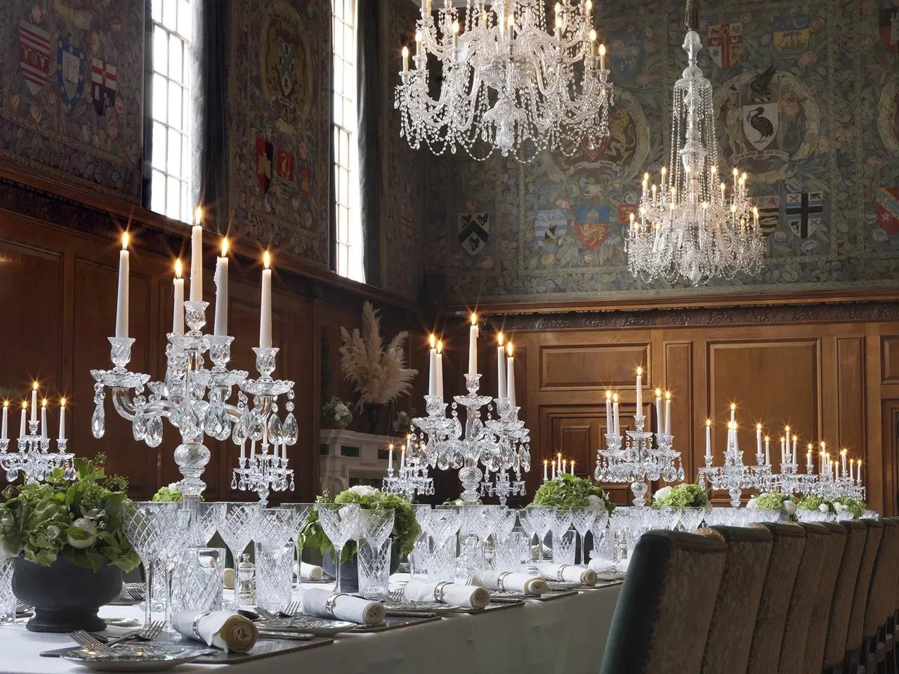 A grand ball room in Victorian style with chandeliers and a wall tapestry set up for a wedding reception
