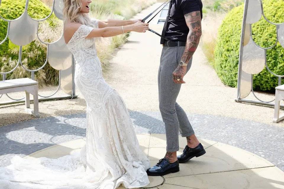 Bride playfully pulling the groom by his braces after the wedding