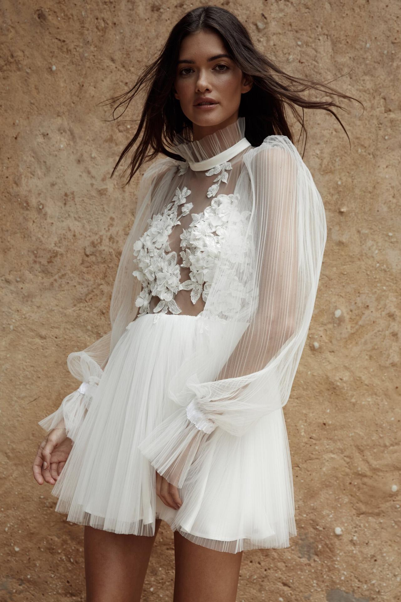 Model wearing a pleated mini long sleeved wedding dress