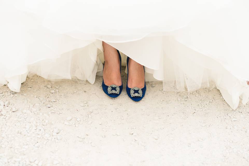 Close up of white bride in a white wedding dress wearing royal blue heels with a crystal clasp at the front