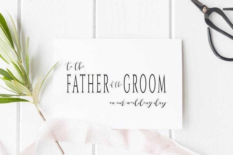 A father of the groom card on a white wooden surface