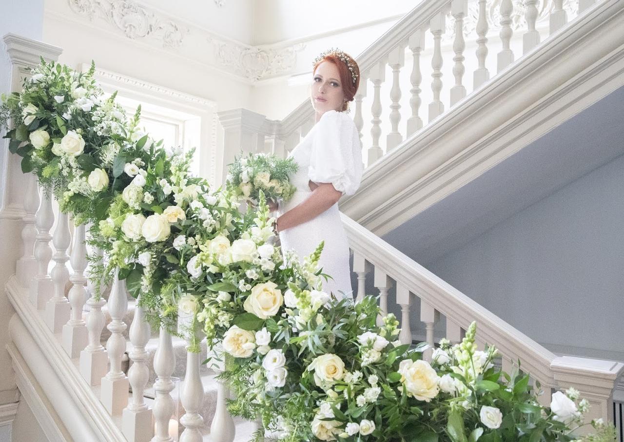 Bride on a staircase decorated in white flowers