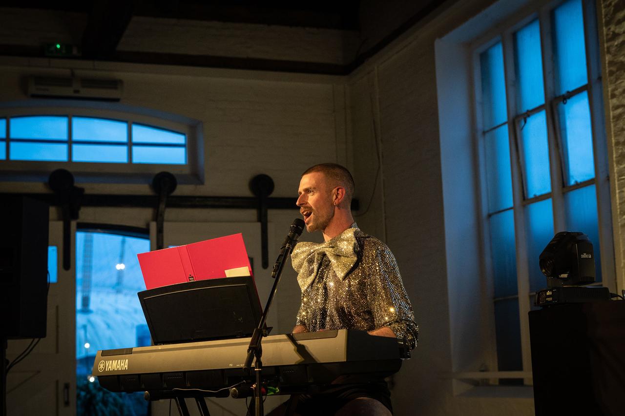 A man wearing a sparkling shirt and bow tie sings