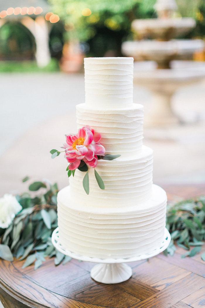 Textured simple wedding cake with a single pink flower