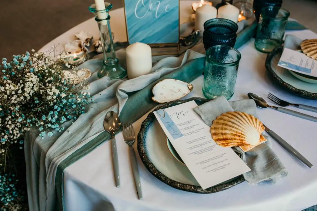 White and blue wedding decorations on a white table on a beach