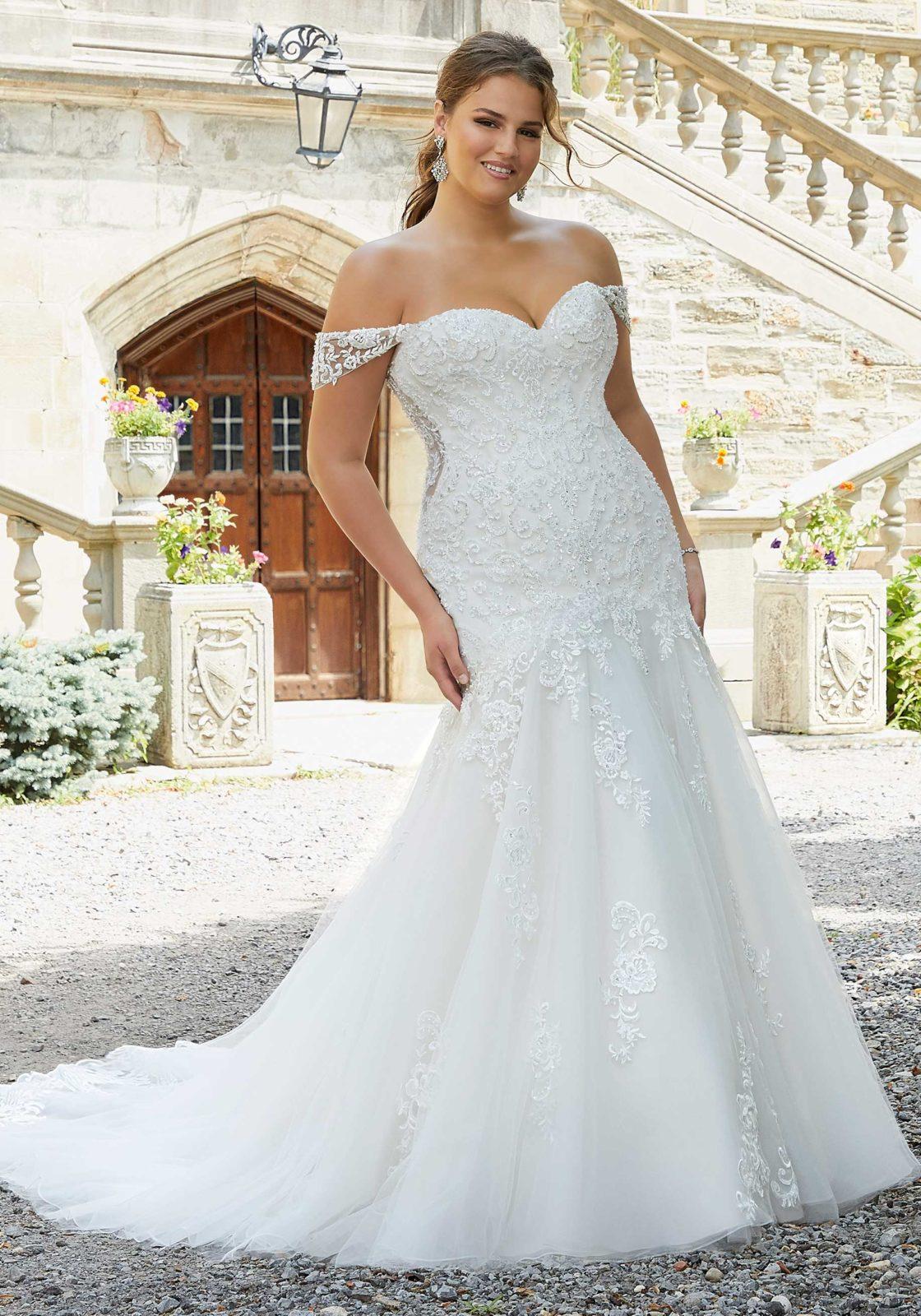 Model wearing a beaded wedding gown with a mermaid silhouette and removable cap sleeves