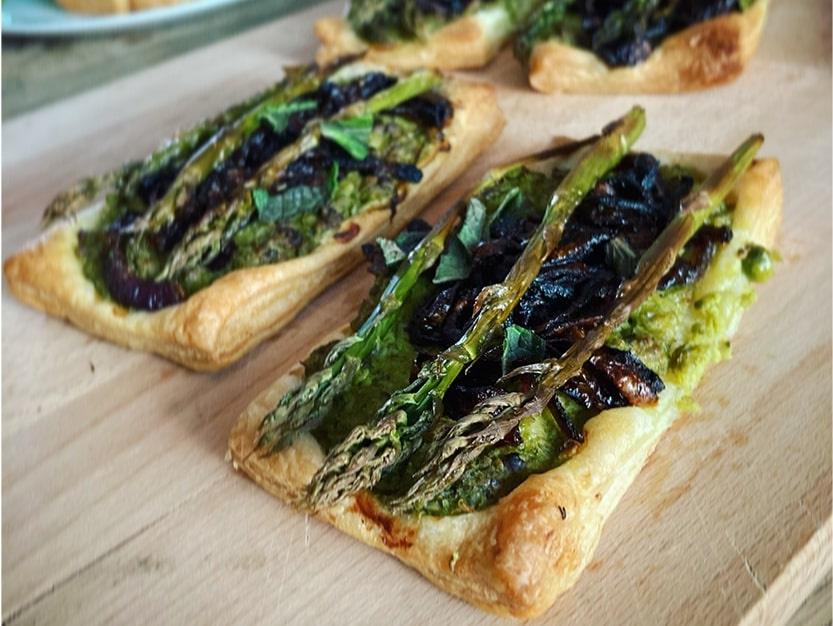 onion and asparagus tarts on a wooden chopping board