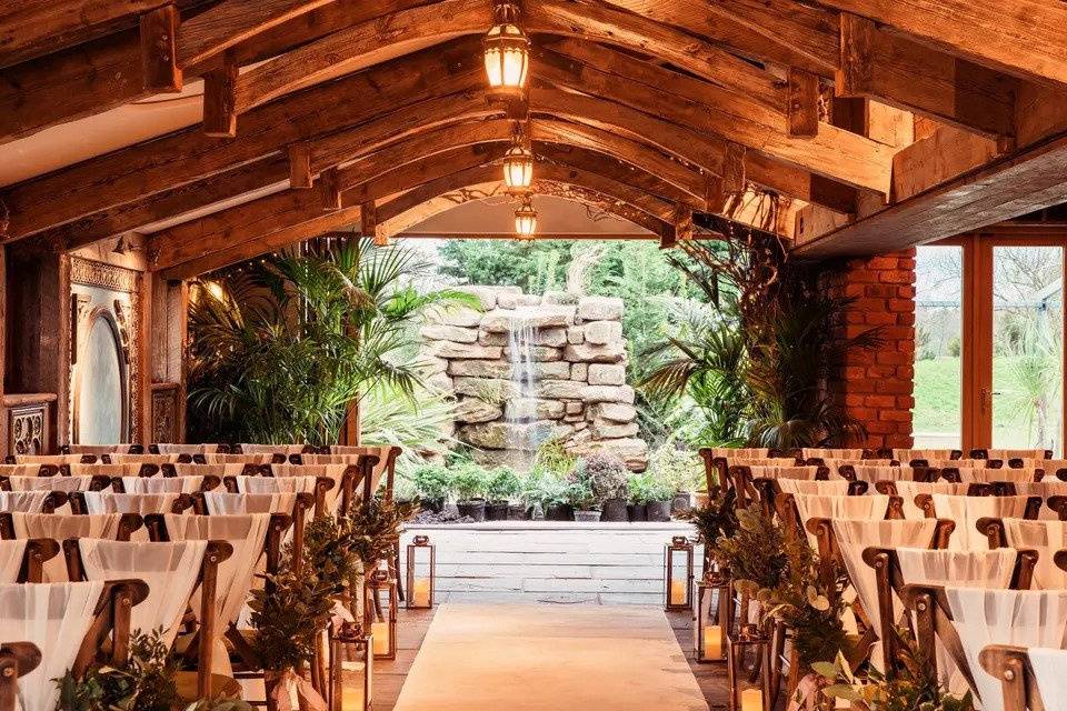 Room set up for wedding ceremony with wooden chairs, an aisle li