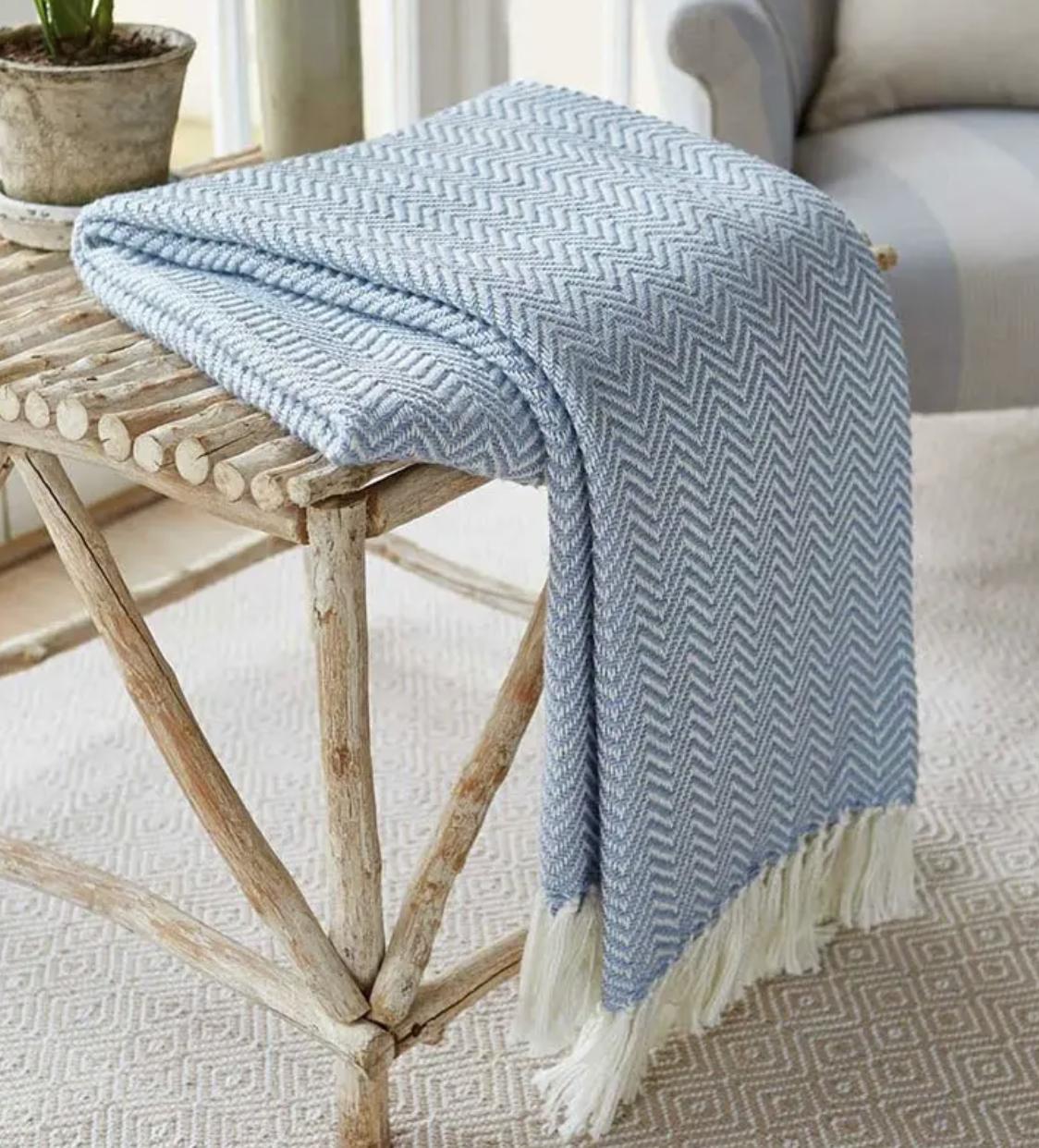 blue herringbone throw folded over a rustic table in a cosy home