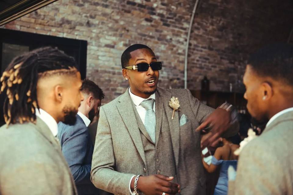 best man wearing a beige suit and sunglasses
