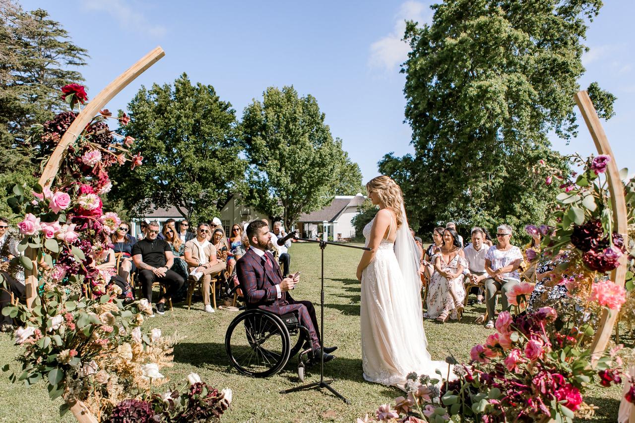 A shot of the bride and groom at the outdoor altar with guests, friends and family sat watching
