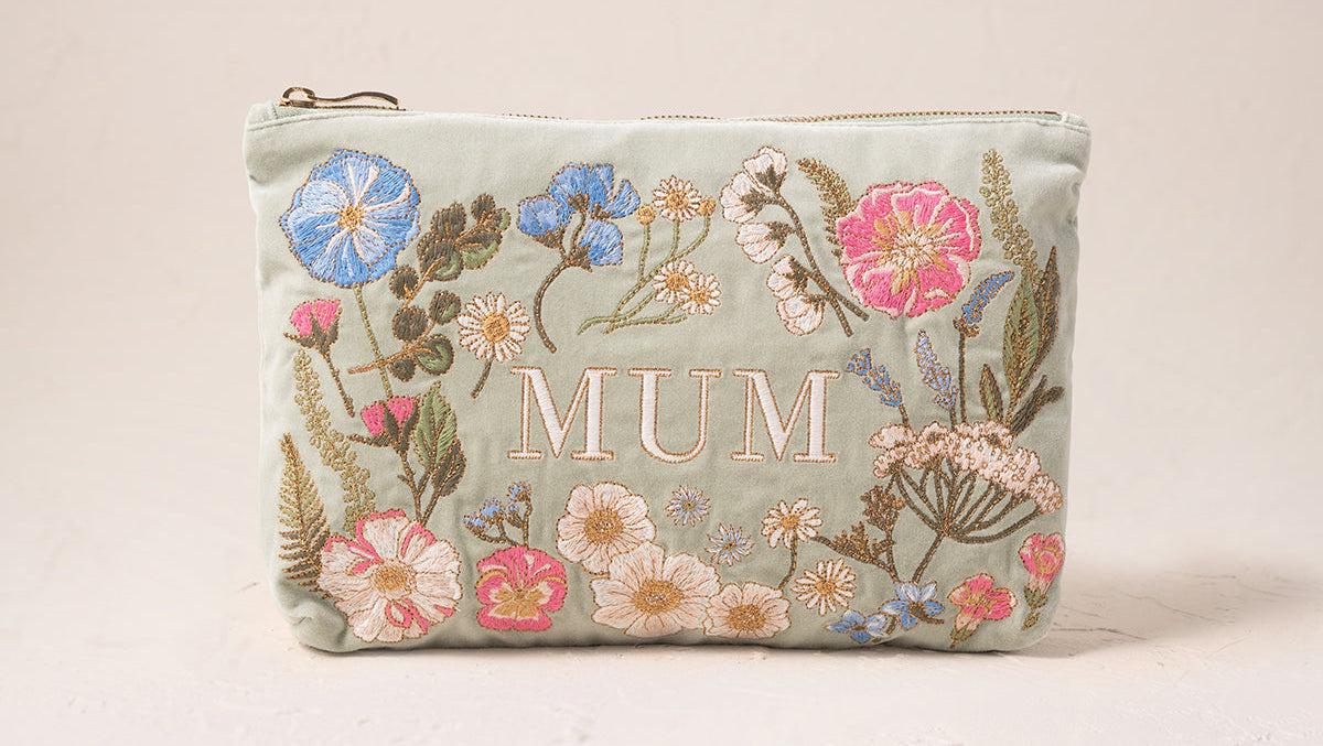 A sage green coloured pouch that reads 'MUM' in embroidery, decorated with colourful floral embroidery.
