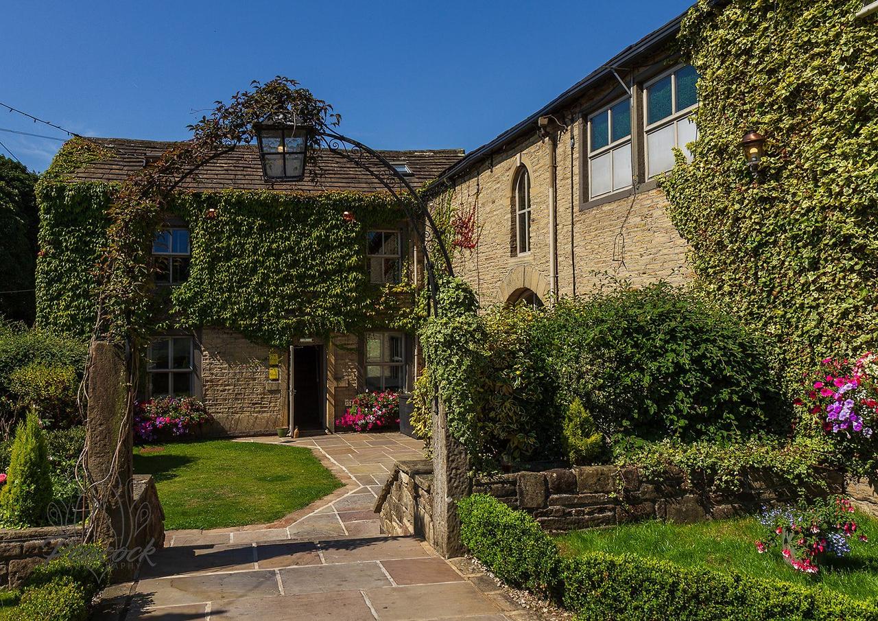 Exterior of a Grade II listed country inn wedding venue covered with ivy and surrounded by flowers.