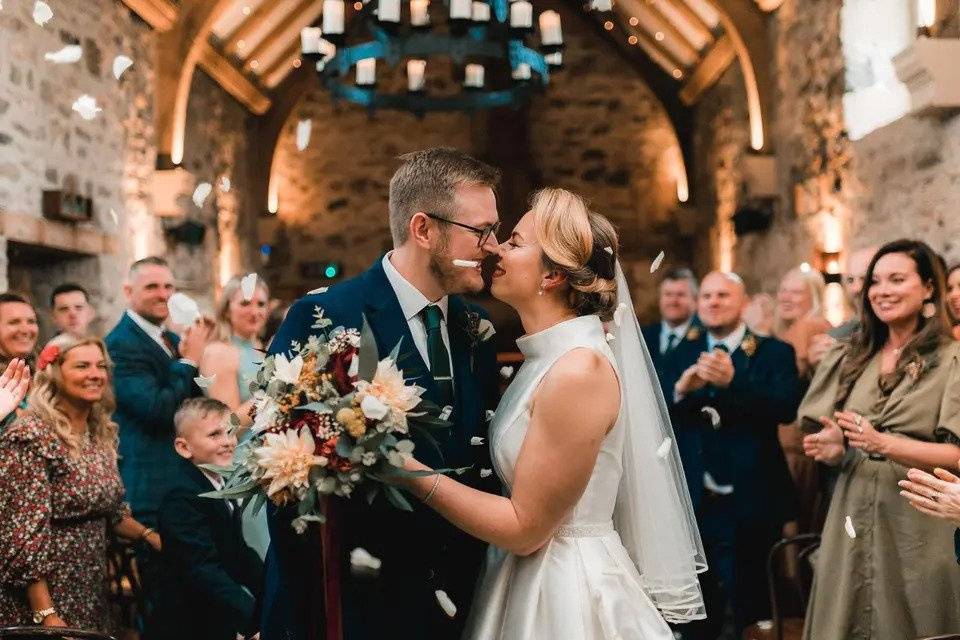 Bride and groom embrace in front of their friends and families inside a church wedding venue