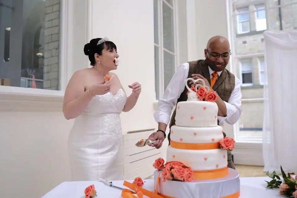 Bride and groom having fun cutting the cake